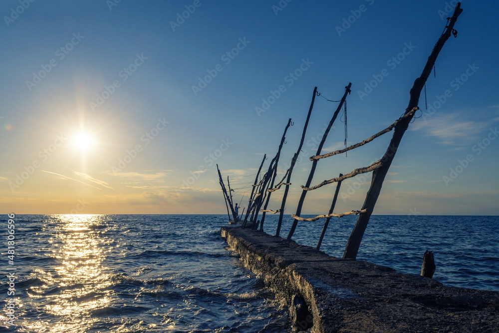 Panorama of an old pier and a fisherman at sunset time on Croatian coast Panorama of an old pier and a fisherman at sunset time on Croatian coast
