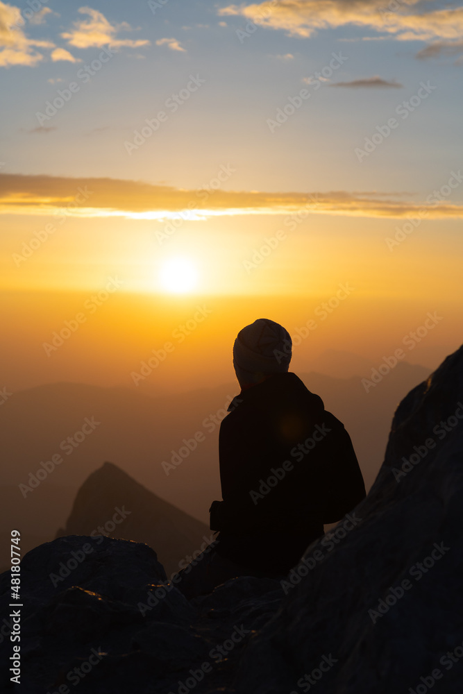 Silhouette of person watching sunrise form top of mountain
