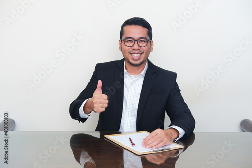 Asian manager wearing black suit give good evaluation sign during interview process photo