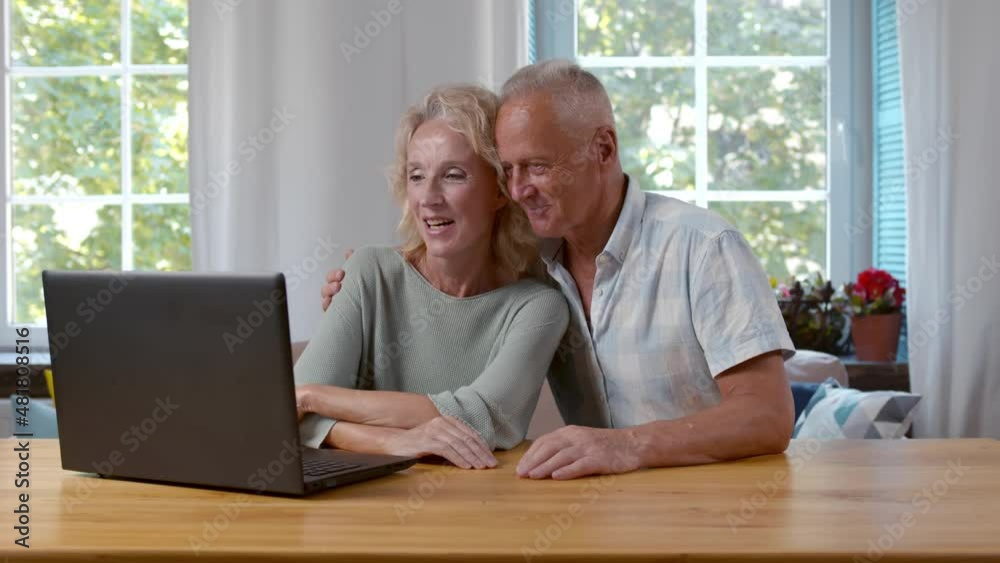 Happy senior couple surfing internet on laptop together at home. Realtime Happy senior couple surfing internet on laptop together at home. Realtime