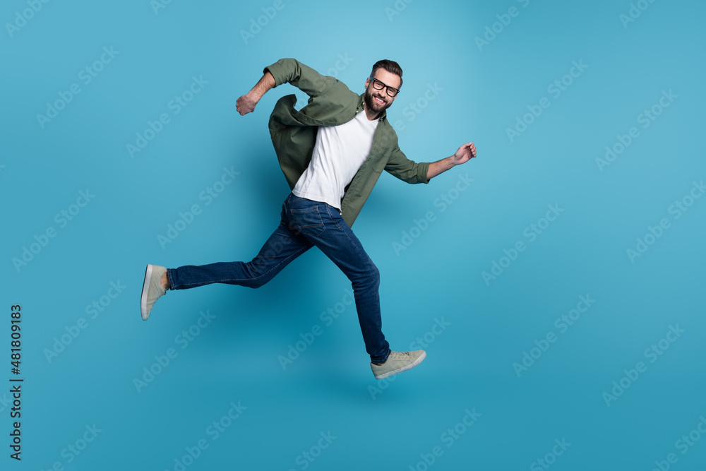 Profile photo of cheerful nice guy jump sporty run wear specs green shirt jeans isolated blue color background