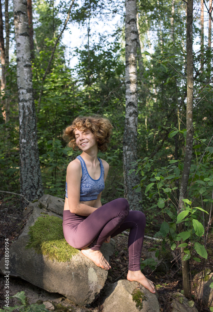 happy joyful teenage girl in sportswear with tousled hair sits on a stone in the forest. Enjoy the happy moment, positive thinking, pleasant dreams. Healthy lifestyle happy joyful teenage girl in sportswear with tousled hair sits on a stone in the forest. Enjoy the happy moment, positive thinking, pleasant dreams. Healthy lifestyle