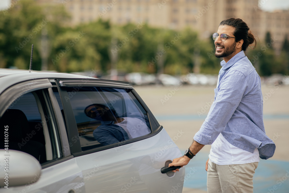 Cheerful middle-eastern man in casual getting in taxi