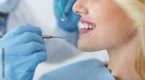 Fototapeta Naklejka Na Ścianę i Meble -  Cropped of young smiling woman and dentist hands with tools
