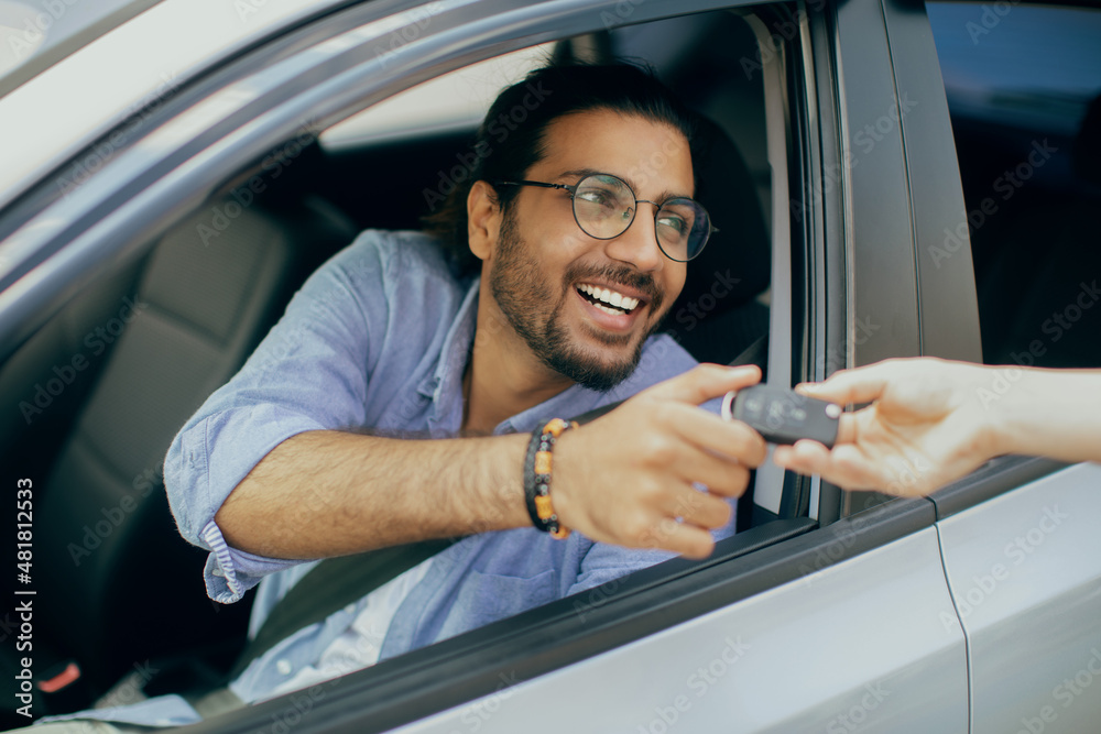 Handsome middle-eastern man taking car key from leasing service person