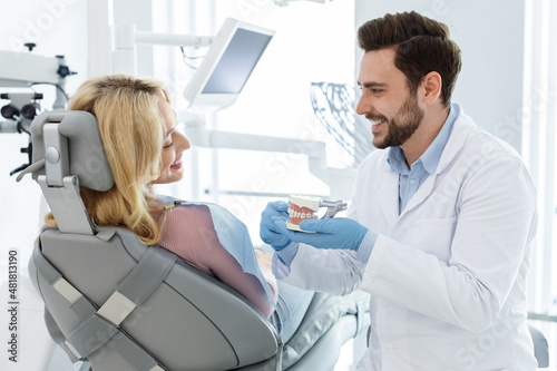 Cheerful man doctor dentist showing jaw miniature to patient