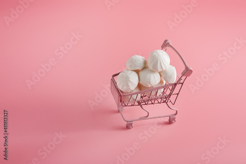 pink grocery basket on a pink background with marshmallows