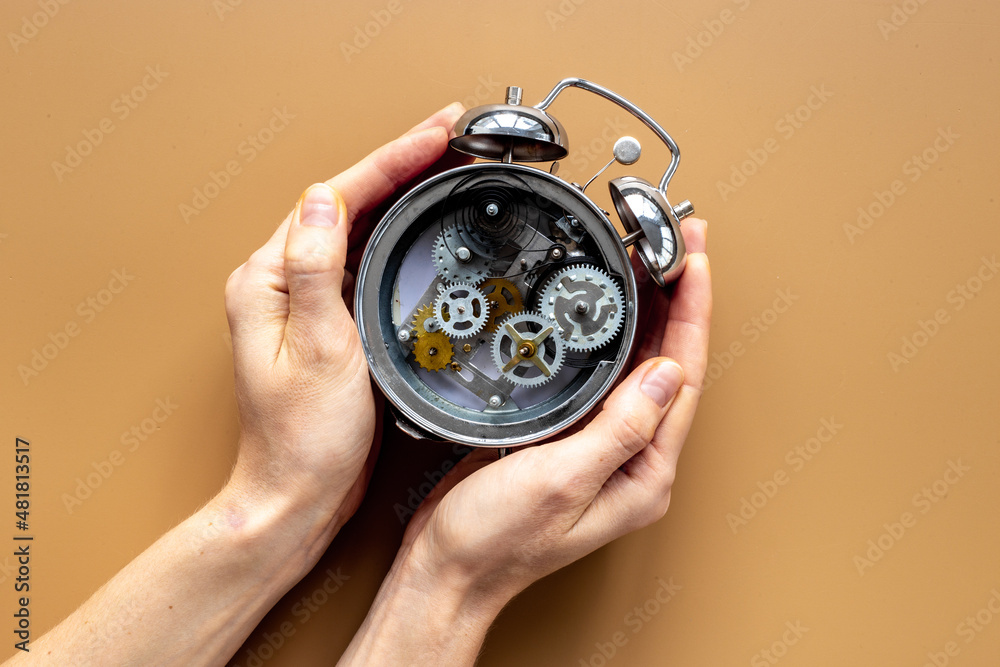 Hands holding alarm clock mechanism with steel gears and wheels close up Hands holding alarm clock mechanism with steel gears and wheels close up