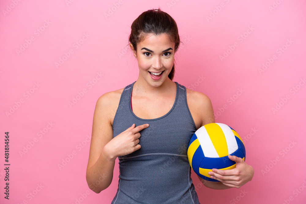 Young Brazilian woman playing volleyball isolated on pink background with surprise facial expression