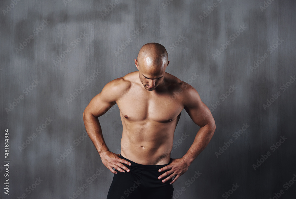 Your earn your body. A shirtless sportsman standing against a gray background.