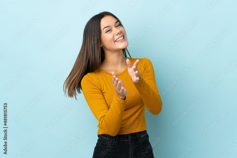 Teenager girl isolated on blue background applauding after presentation in a conference Teenager girl isolated on blue background applauding after presentation in a conference