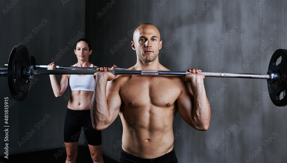 Shaping up at the gym. Shot of two people lifting barbells during a gym workout. Shaping up at the gym. Shot of two people lifting barbells during a gym workout.