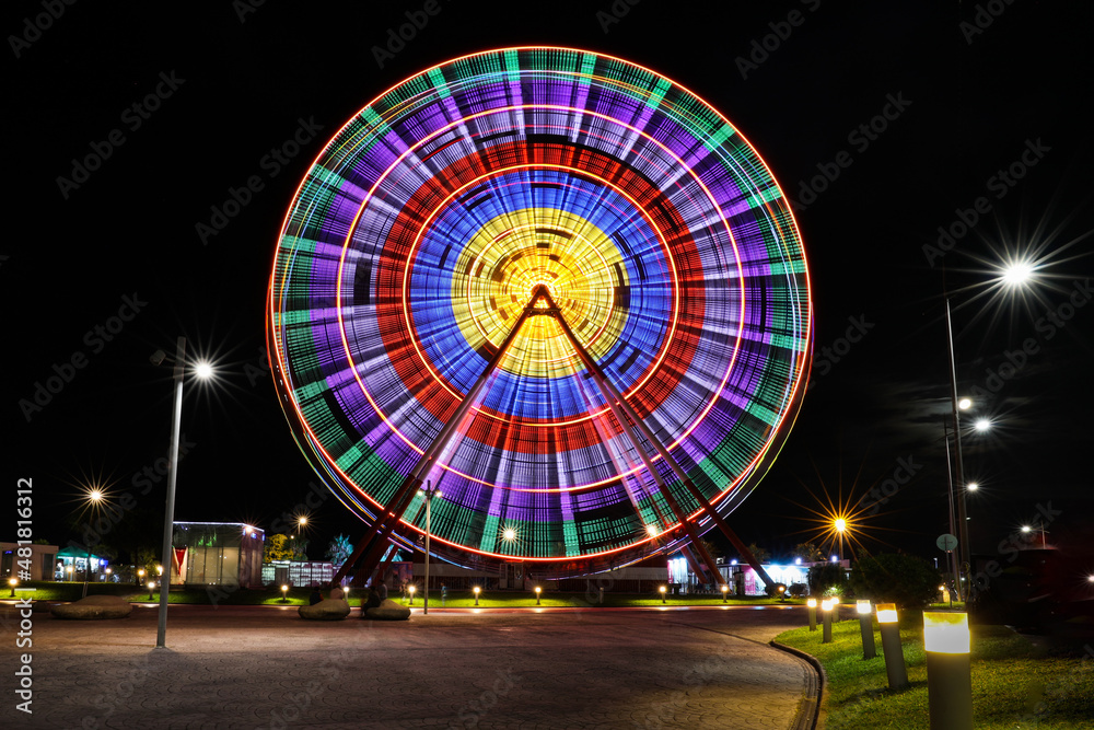 Bright backlit ferris wheel, blurred by a slow shutter speed