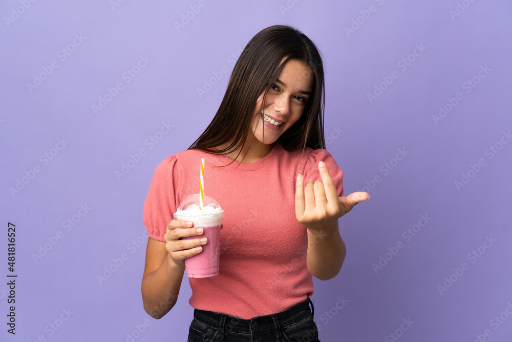 Teenager girl holding a strawberry milkshake inviting to come with hand. Happy that you came