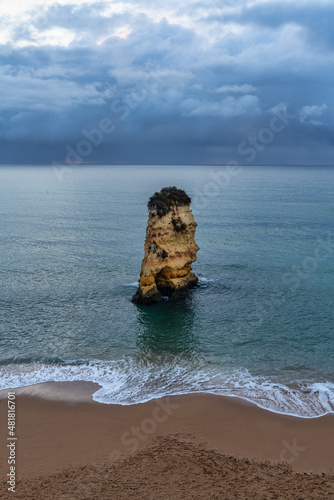 islet rock on Dona Ana beach with dramatic sky  in Lagos  Algarve  Portugal