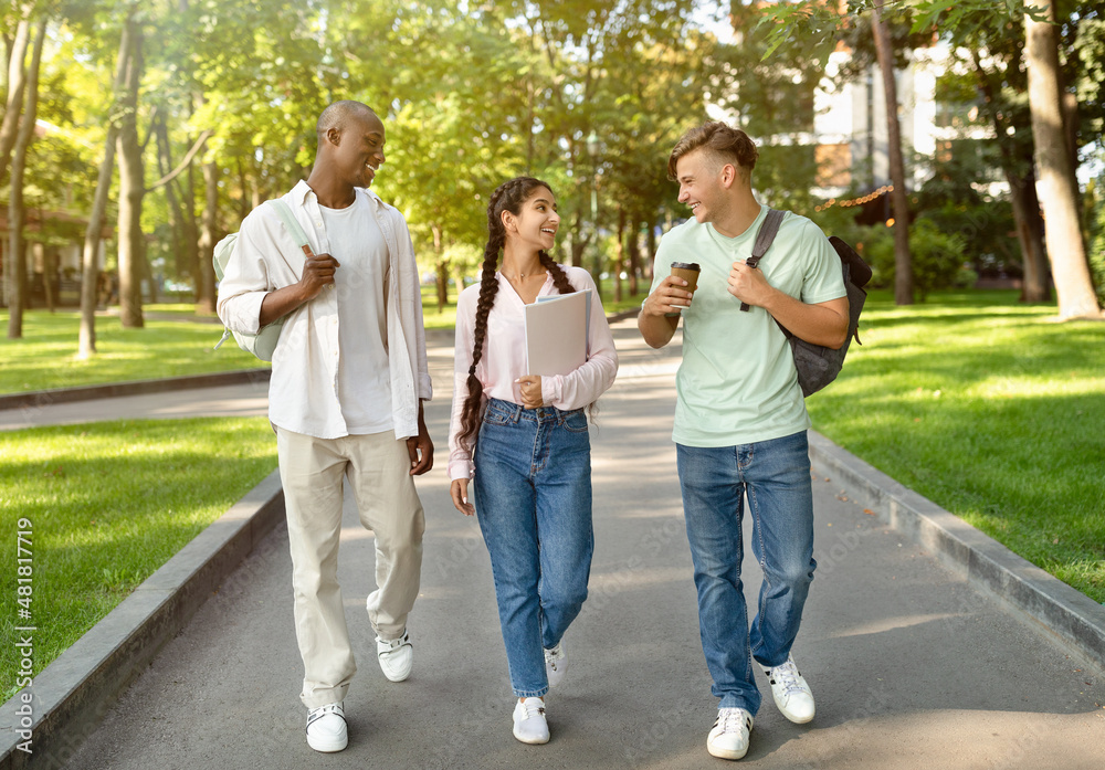 Three multiracial high-school students walking after study and talking in university campus outdoors Three multiracial high-school students walking after study and talking in university campus outdoors