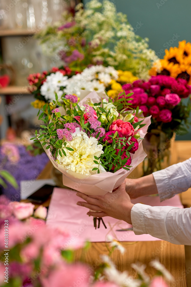 people, shopping, sale, floristry and consumerism concept. close-up woman hands giving flowers to client at flower shop. beautifully made prepared bouquet on 8 march or another holiday