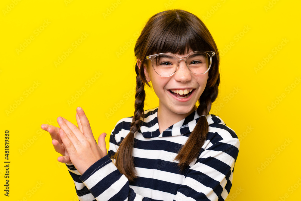 Little caucasian girl isolated on yellow background With glasses and applauding Little caucasian girl isolated on yellow background With glasses and applauding