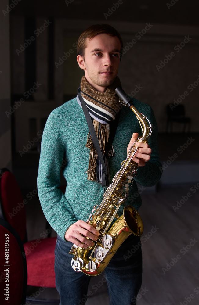 Fototapeta premium Young guy music artist jazzman holding a saxophone in his hands.