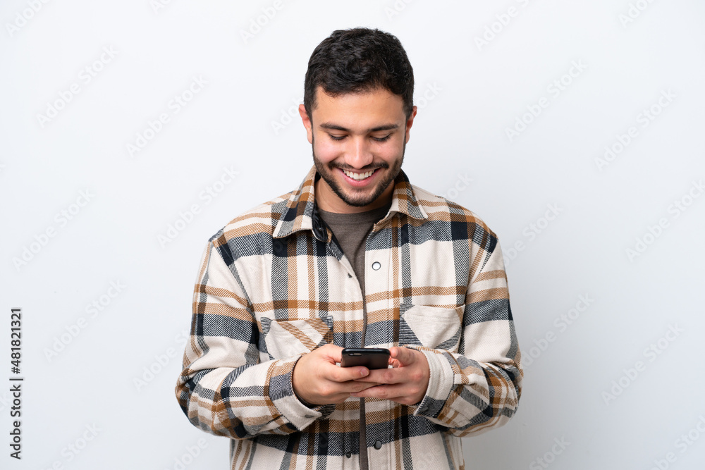 Young Brazilian man isolated on white background sending a message with the mobile Young Brazilian man isolated on white background sending a message with the mobile