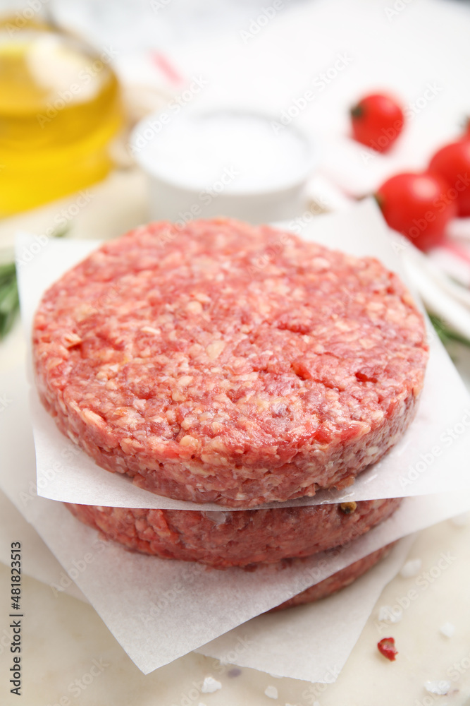 Raw hamburger patties with rosemary and salt on board, closeup Raw hamburger patties with rosemary and salt on board, closeup