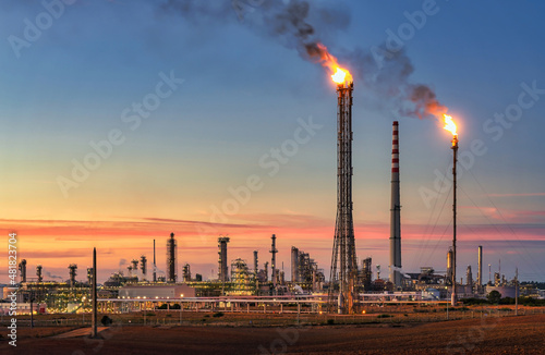 Quadro su tela Sines refinery, Portugal at sunset with chimneys giving off flames and smoke