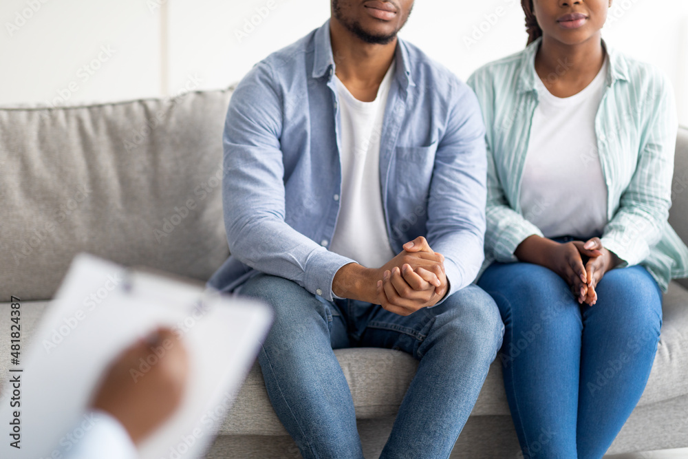 Cropped view of young black married couple on consultation with psychologist, undergoing family therapy at clinic