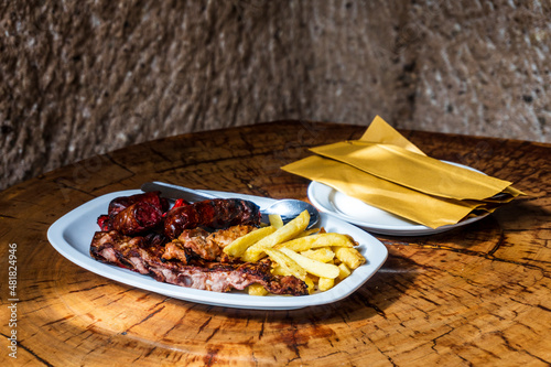 Mixed meat barbecued and served with french fries in restaurant in the cave, Guayadeque Ravine, Gran Canaria, Spain photo