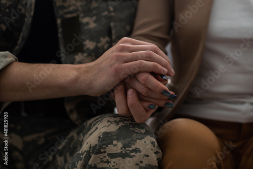Military man and girlfriend holding hands, supporting boyfriend before leaving