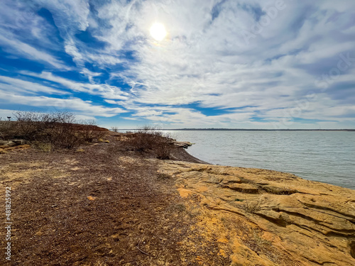 Wide angle view the sandstone cliff and rocky shoreline with picnic area bluffs overlooking lake at Murrell Park, Grapevine Lake, Texas