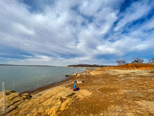 Bank fishing poles on rocky shoreline and dropoffs along North side of Grapevine Lake in Texas, America