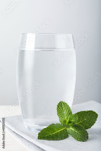 Glass of soda water, mint and napkin on white wooden table