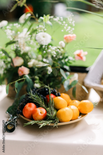 A fruit plate. Various fruits with rosemary on the table. Black grapes  nectarines  tangerines and green apples. 