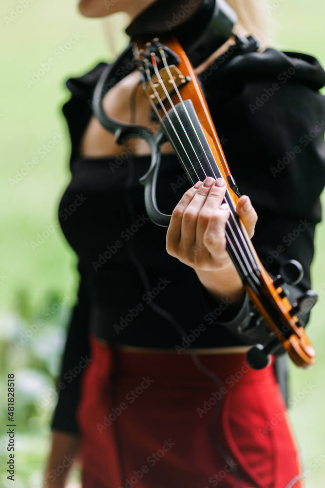A girl playing an electronic violin. playing an instrument. violin close-up. The idea of classes during quarantine. The concept of music. A girl playing an electronic violin. playing an instrument. violin close-up. The idea of classes during quarantine. The concept of music.