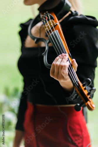 A girl playing an electronic violin. playing an instrument. violin close-up. The idea of classes during quarantine. The concept of music. 