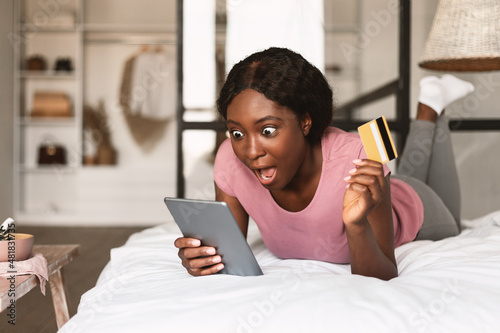 Shocked Black Lady Using Credit Card And Tablet Shopping Indoor