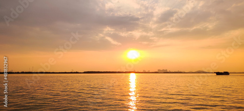 Sunset or sunrise in ocean with buildings, boat and buildings in distance © James Jiao