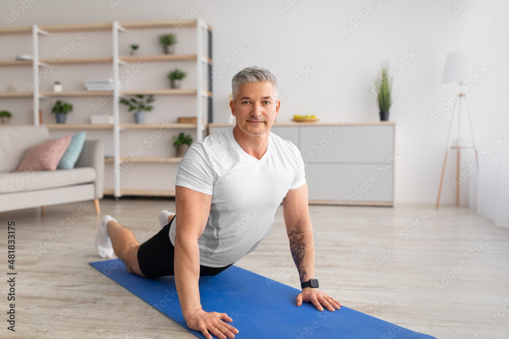 Mature man stretching back muscles, doing sphinx cobra pose or upward-facing dog asana, empty space Mature man stretching back muscles, doing sphinx cobra pose or upward-facing dog asana, empty space