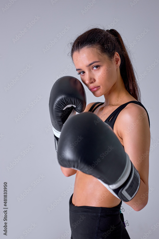 good-looking sports fitness boxer woman in black sportswear working out isolated in studio background. Sport exercise healthy lifestyle concept. Make boxing exercises in boxing gloves