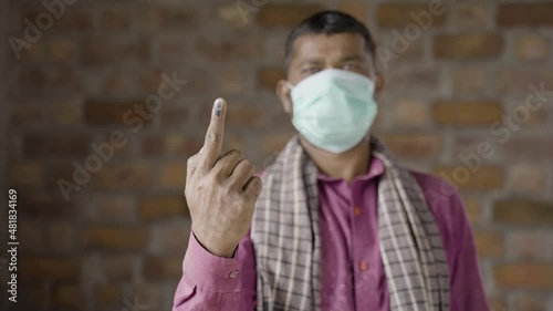 fack fous shot, Construction worker with medical face mask showing ink marked finger after voting in election by looking camera - concept of democracy and Indian poll system photo