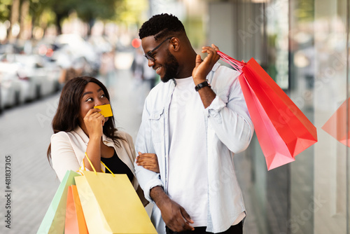 Portrait of happy afro woman showing credit card to man