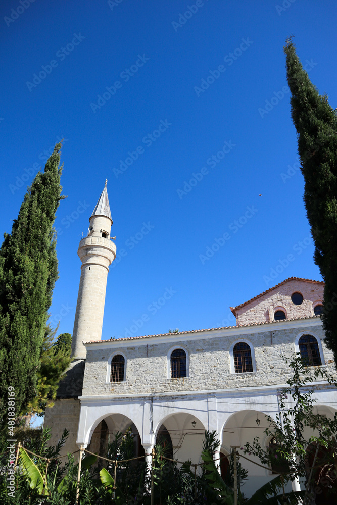 old mosque in small turkish city Alacati on blue sky background