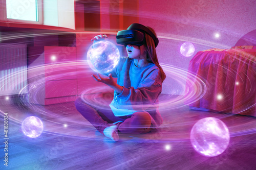 Child girl wearing virtual reality headset and looking at digital space system with planets or Universes. Space exploration with augmented reality glasses.  photo