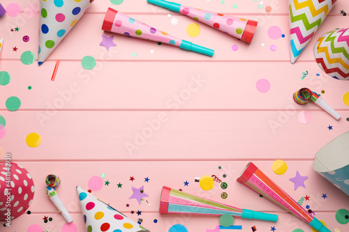 Frame of party items on pink wooden table, flat lay. Space for text