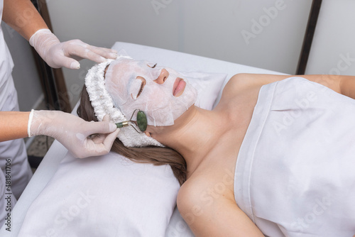 young woman in beauty center performing radio frequency therapy of facial complexion for skin beauty, applied by a beautician photo