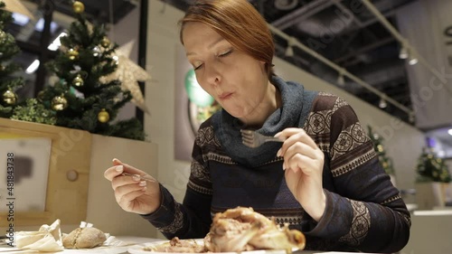 a woman eats fried pork knuckle with broccoli in a restaurant