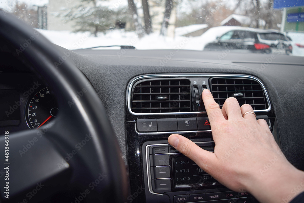 The driver 's hand adjusting the air conditioner on the panel in the car interior The driver 's hand adjusting the air conditioner on the panel in the car interior