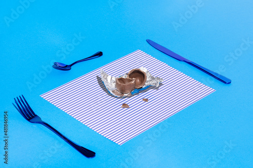 Broken chocolate egg on a plate on a blue background photo