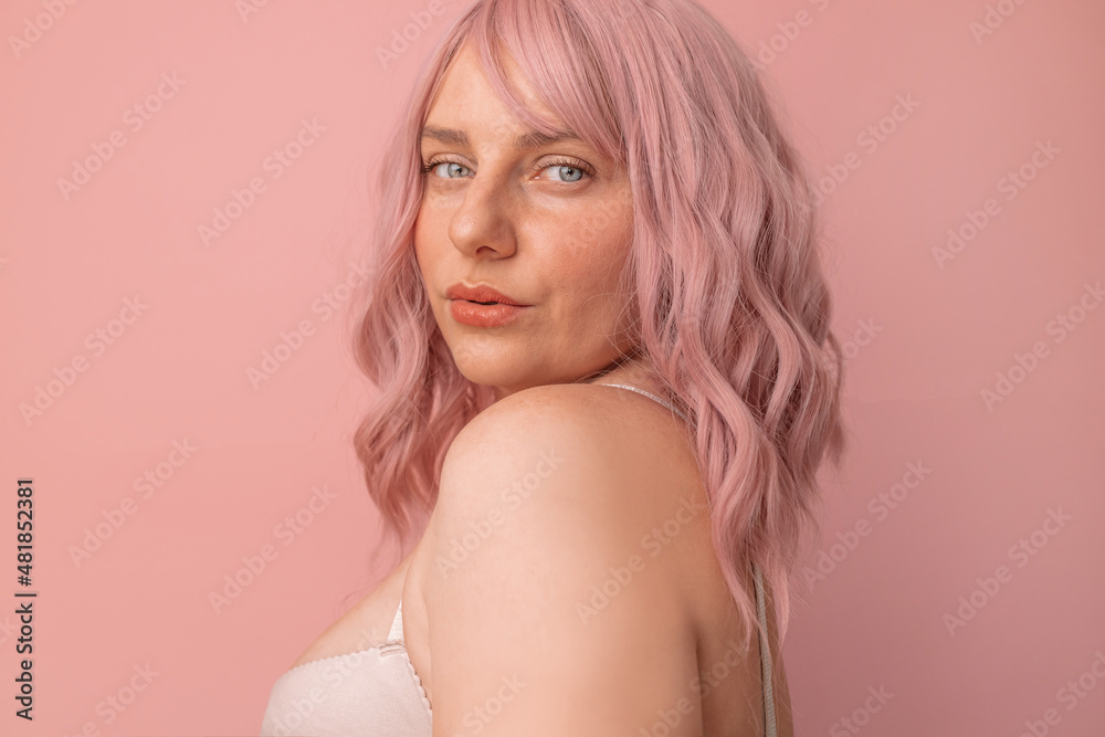 Portrait of pretty sexy girl with pink curly hair in lingerie posing isolated on pink background Portrait of pretty sexy girl with pink curly hair in lingerie posing isolated on pink background
