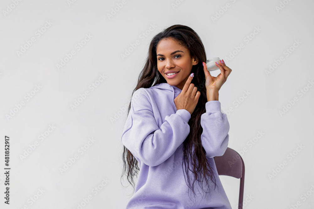 Young african american woman applying cream on her face Young african american woman applying cream on her face